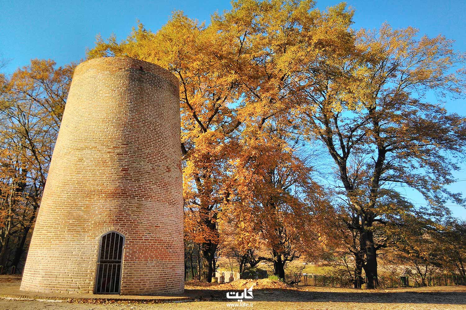 یک برج آجری در کنار درختان پاییزی