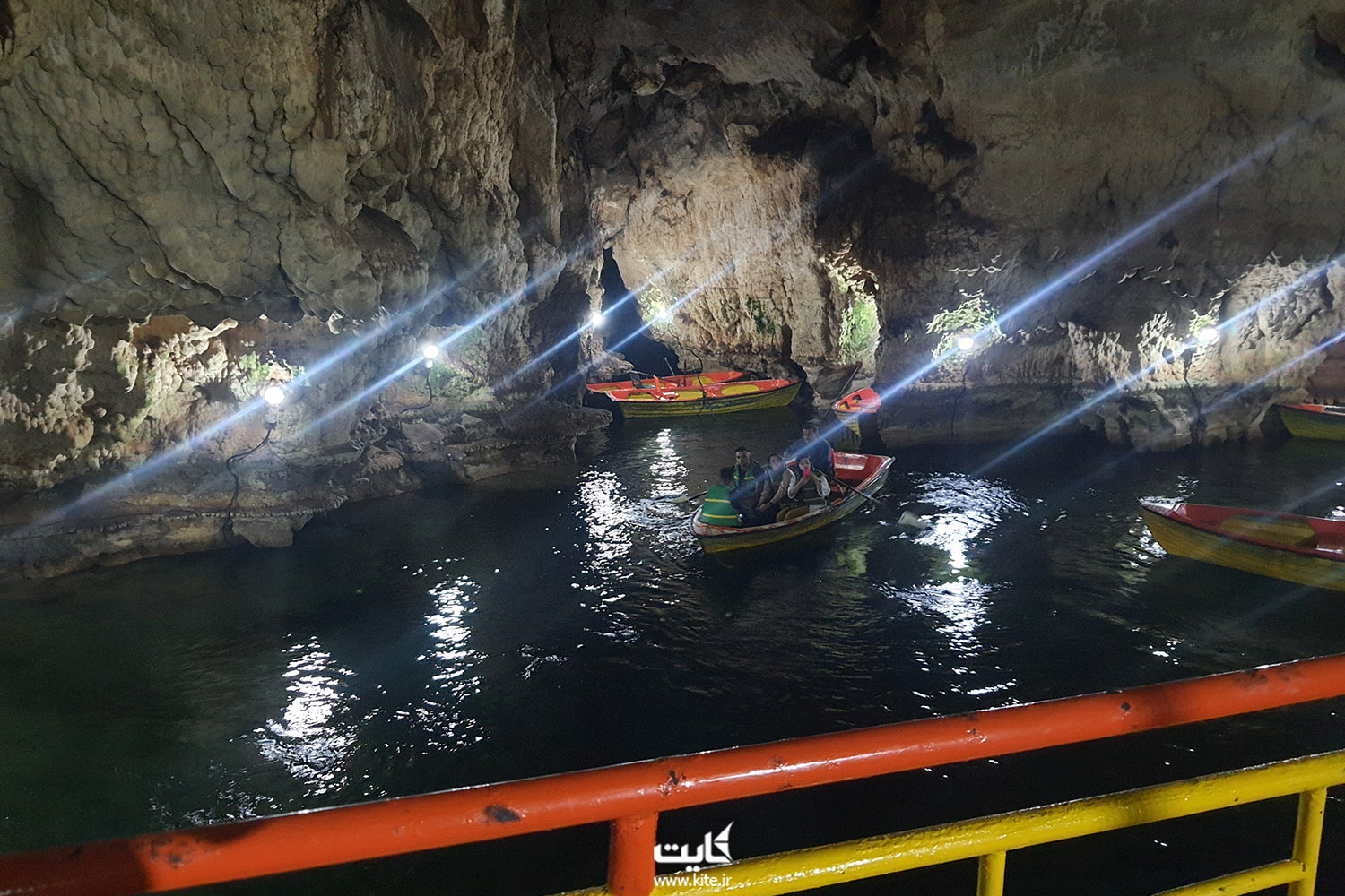 دیواره های سنگی و حوضچه آبی داخل غار قایق و چند گردشگر